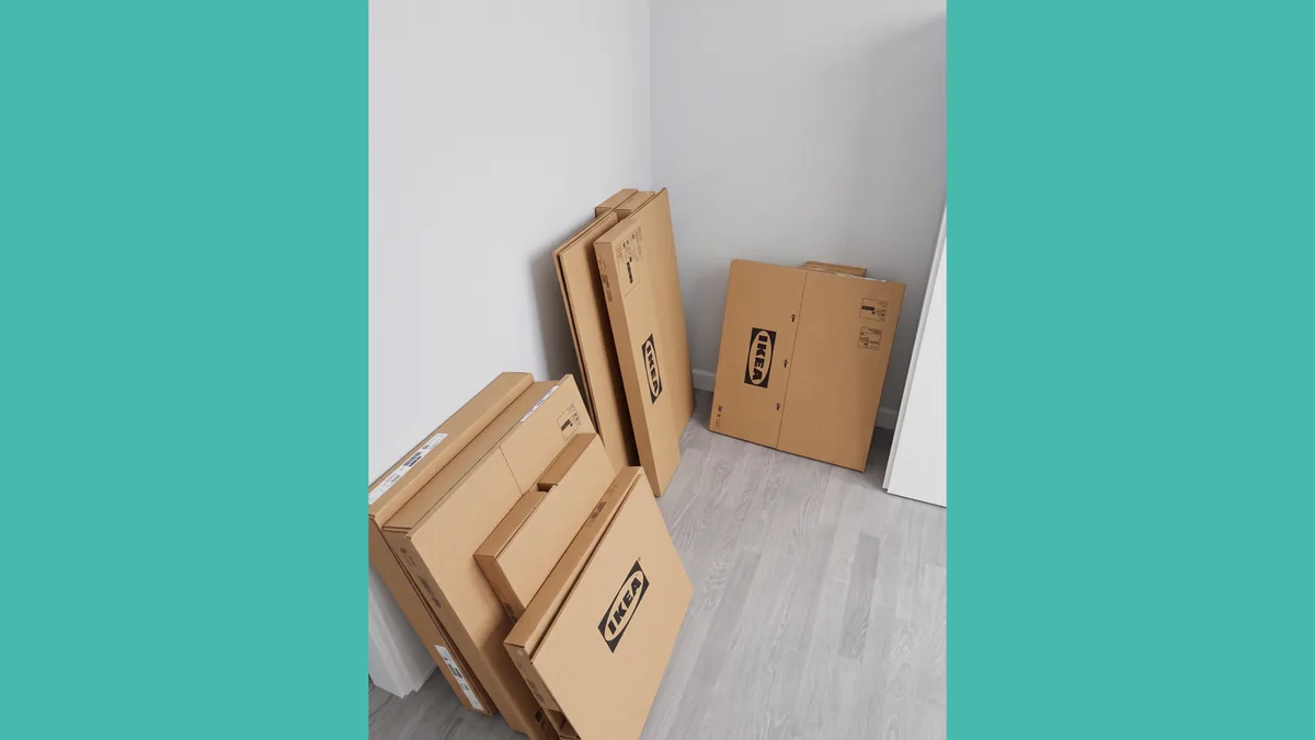 Ihopvikta IKEA-kartonger med PAX-delar sorterade i ett hörn